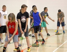 Students practicing golf with colorful beginner equipment in a school gym